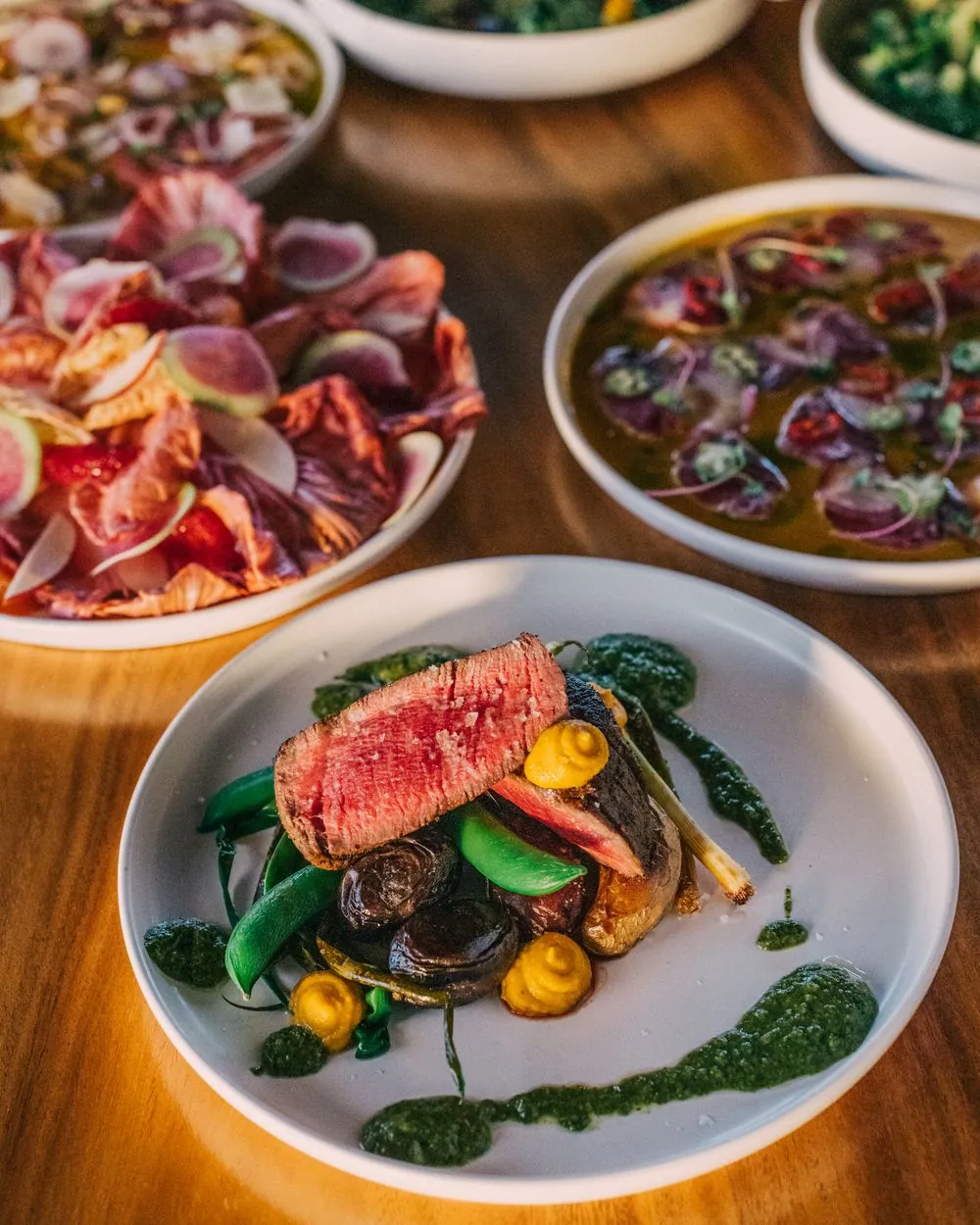 Sliced steak plate with shared dishes across the table